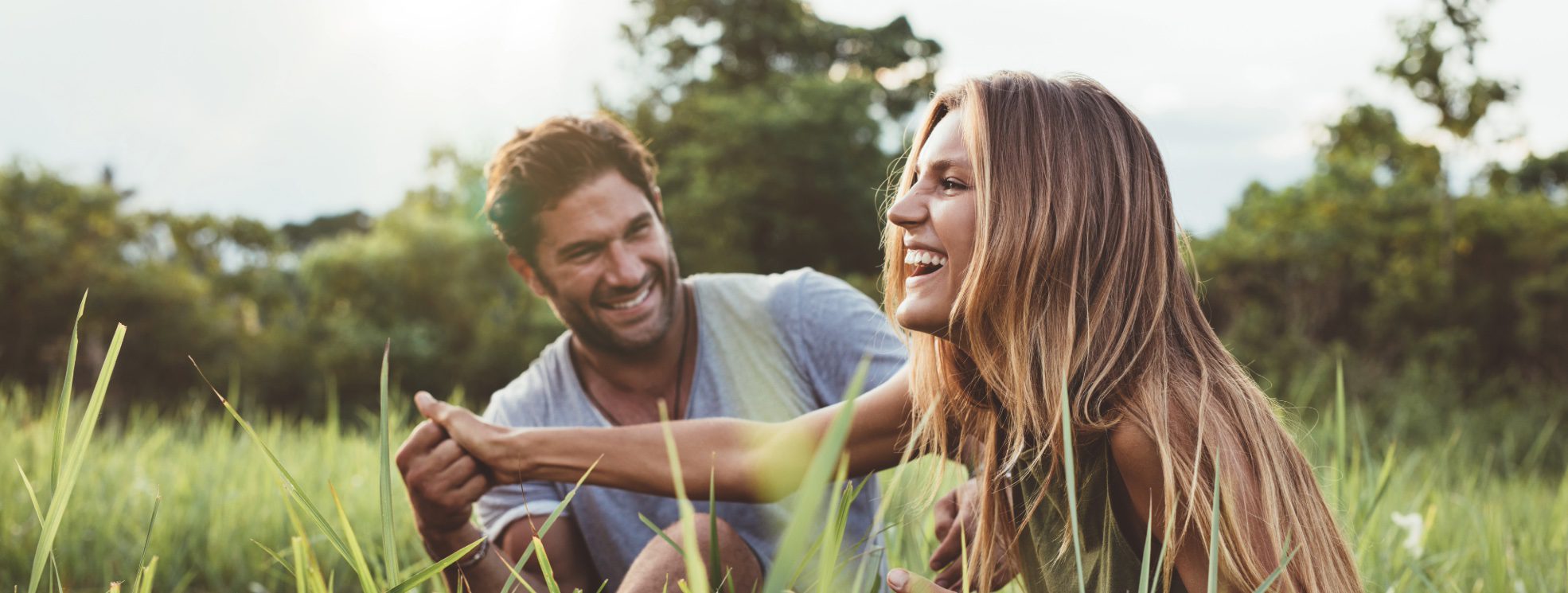 Smiling couple sitting together in a sunlit grassy field